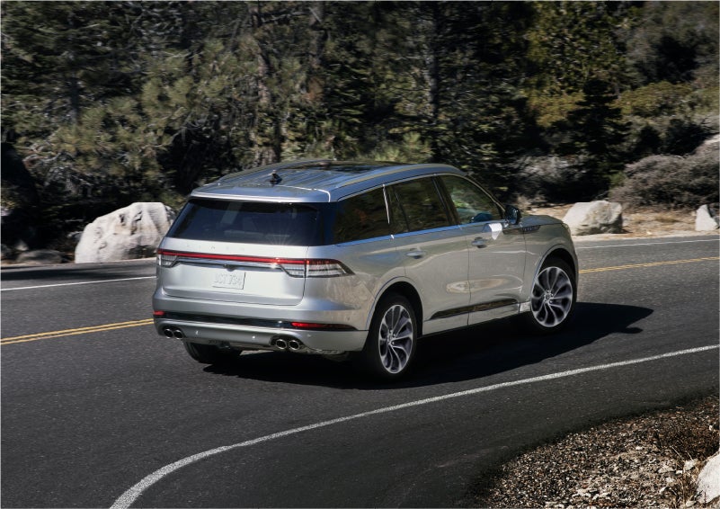 A 2023 Lincoln Aviator® Grand Touring model is shown being driven on a tight turn of a mountain road | Lincoln of New Bern in New Bern NC