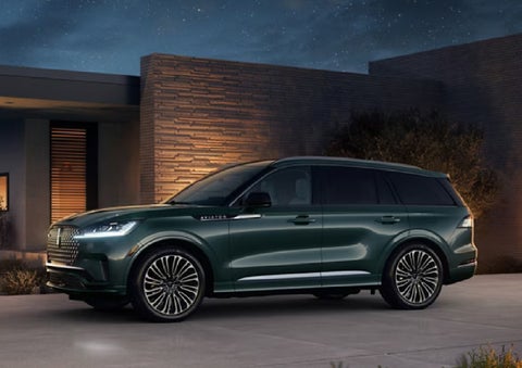 A green 2027 Lincoln Aviator® SUV is parked outside a contemporary home. | Lincoln of New Bern in New Bern NC