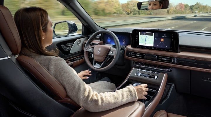 A 2027 Lincoln Aviator® SUV is being driven hands-free on a highway lined with trees. | Lincoln of New Bern in New Bern NC