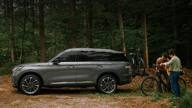 A father and son load e-bikes on a bike rack attached to a 2027 Lincoln Aviator® SUV. | Lincoln of New Bern in New Bern NC