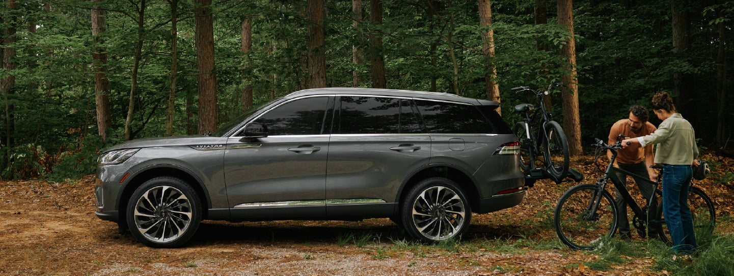 A father and son load e-bikes on a bike rack attached to a 2027 Lincoln Aviator® SUV. | Lincoln of New Bern in New Bern NC